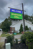 Outdoor LED sign displaying 'WELCOME BINBROOK GRILL' in blue and green colors mounted on a post.