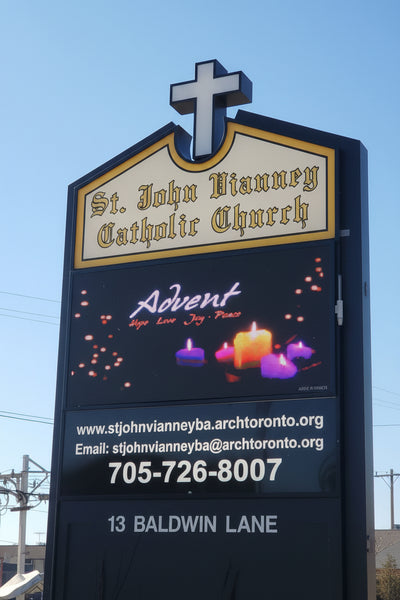 An outdoor LED sign for St. John Vianney Catholic Church featuring the church's name and contact information.