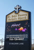 An outdoor LED sign for St. John Vianney Catholic Church featuring the church's name and contact information.